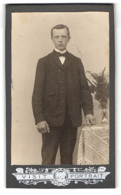 Photograph Portrait of a Young Man Next to a Table with Flower Vase