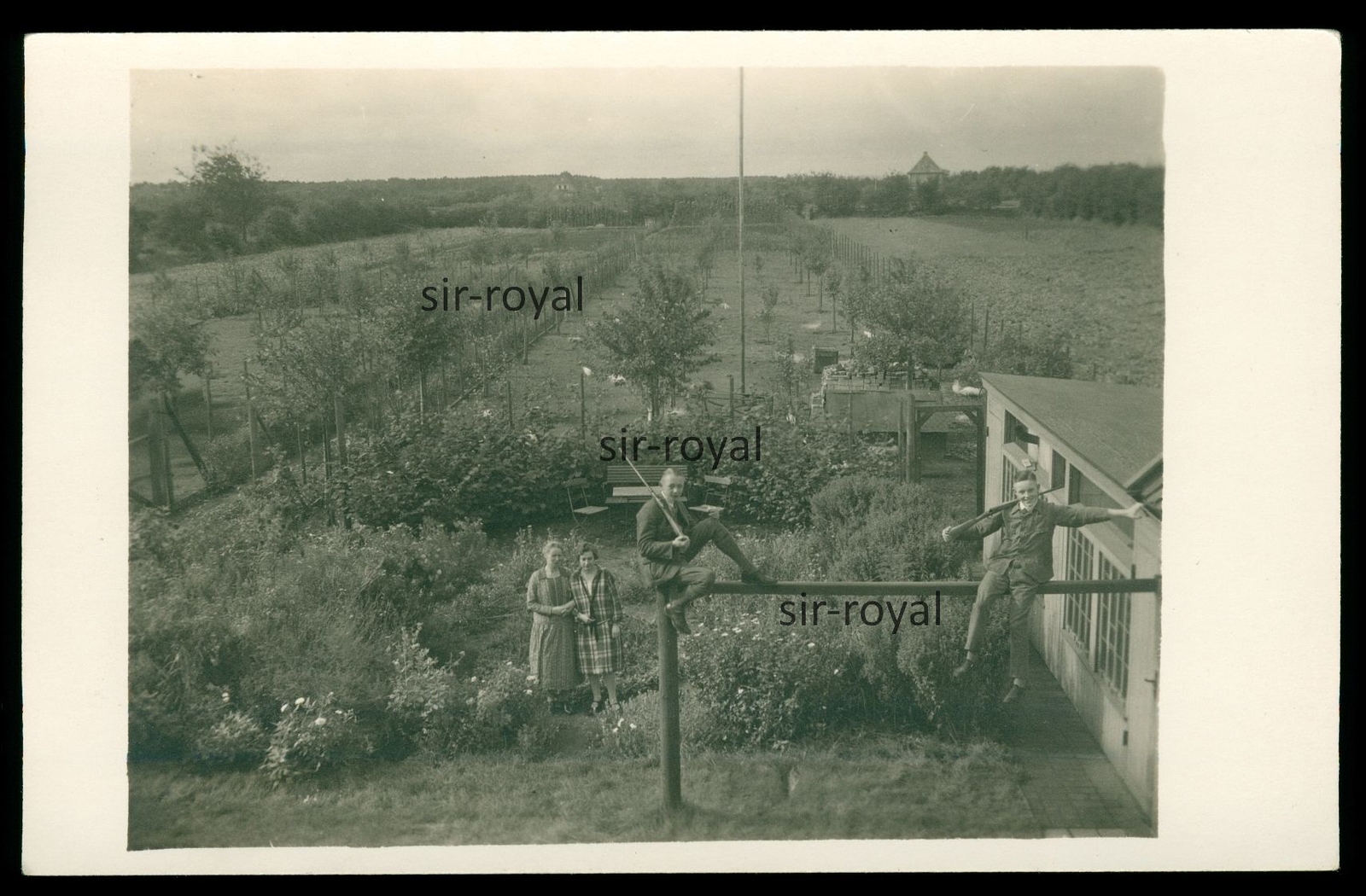 Boys posing with guns in front of beautiful garden – photo postcard 14x9cm