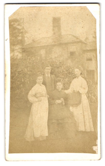 Photograph Four people in a garden in front of a house
